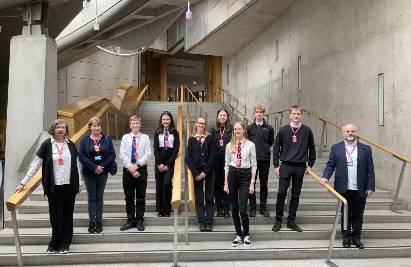 (left-to-right) Pauline Hickman (Instructor), Carolyn Wilson (Instructor), Brodie Wallace (Violinist), Isabella Gold (Violinist), Freya Harley (Celloist), Hannah Swinney (Celloist), Lois Thomson (Violinist), Thomas Bull (Violinist), Michael Hoole (Violinist) and Ewing Lauder (Instructor) at the stair’s leading up to the Scottish Parliament’s Debating Chamber during a guided tour.